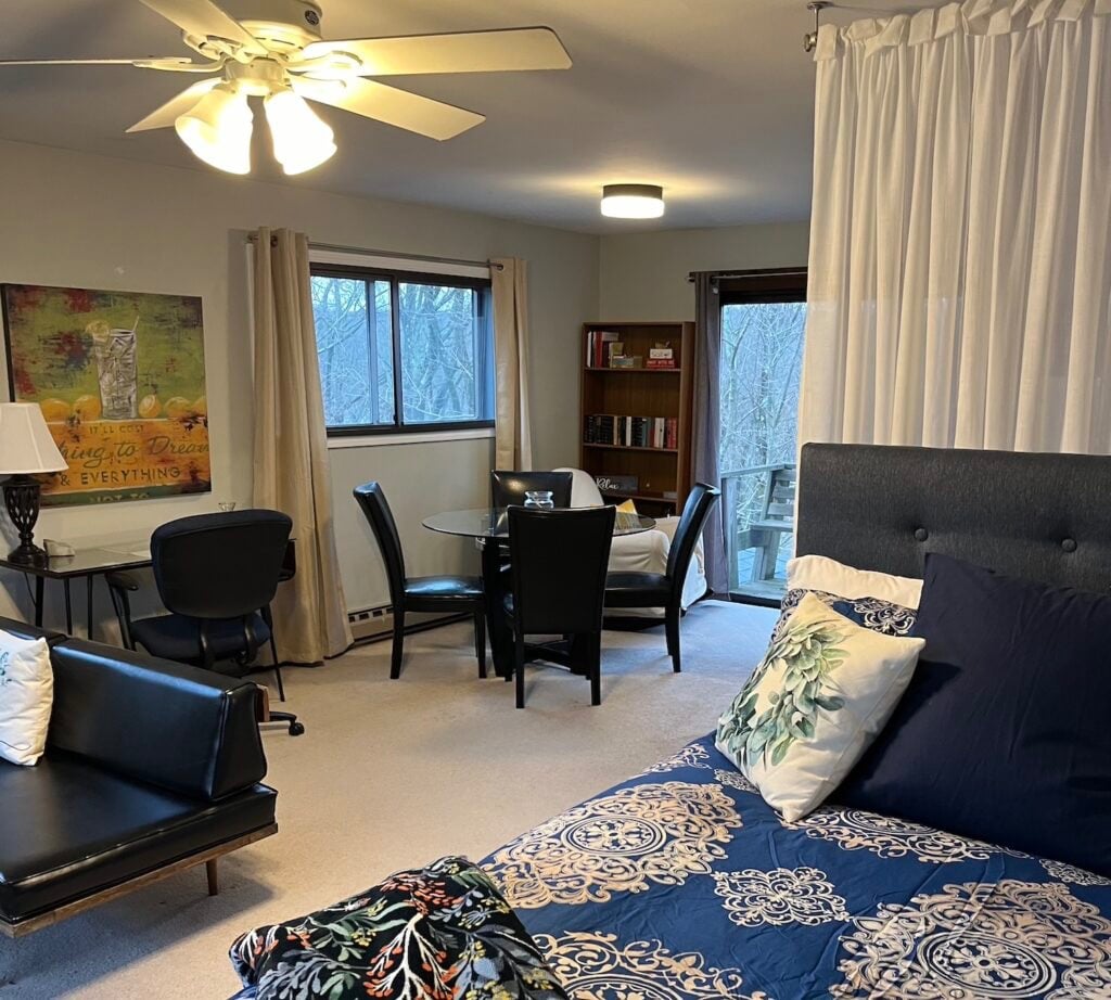 Guest studio with a bed, dining table, and sliding door to a balcony