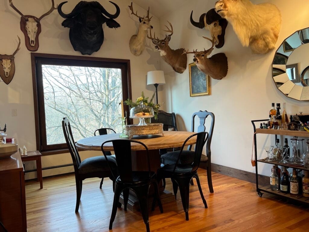 Dining room with a round wood table and a wall of mounts